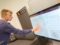 Eine Person zeigt mit einem Finger auf einen großen Bildschirm