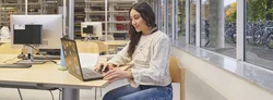 Person arbeitet in der Bibliothek am Laptop
