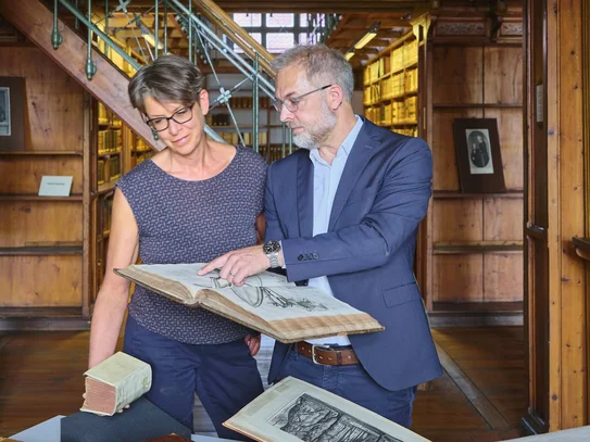 Beratung zu historischen Beständen an der SUB Göttingen Zwei Personen im historischen Bibliothekssaal, eine zeigt der anderen ein altes Buch